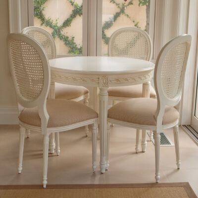 Round back French dining chair in pretty dining setting with cane back painted white and small white round dining table