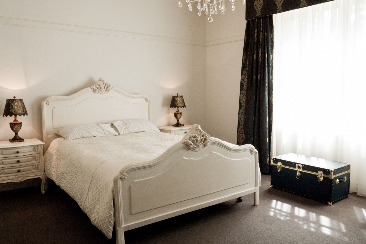 10 French bedroom with white painted bordeaux bed with two Louis XV white bedsides and beautiful table lamps and black curtains