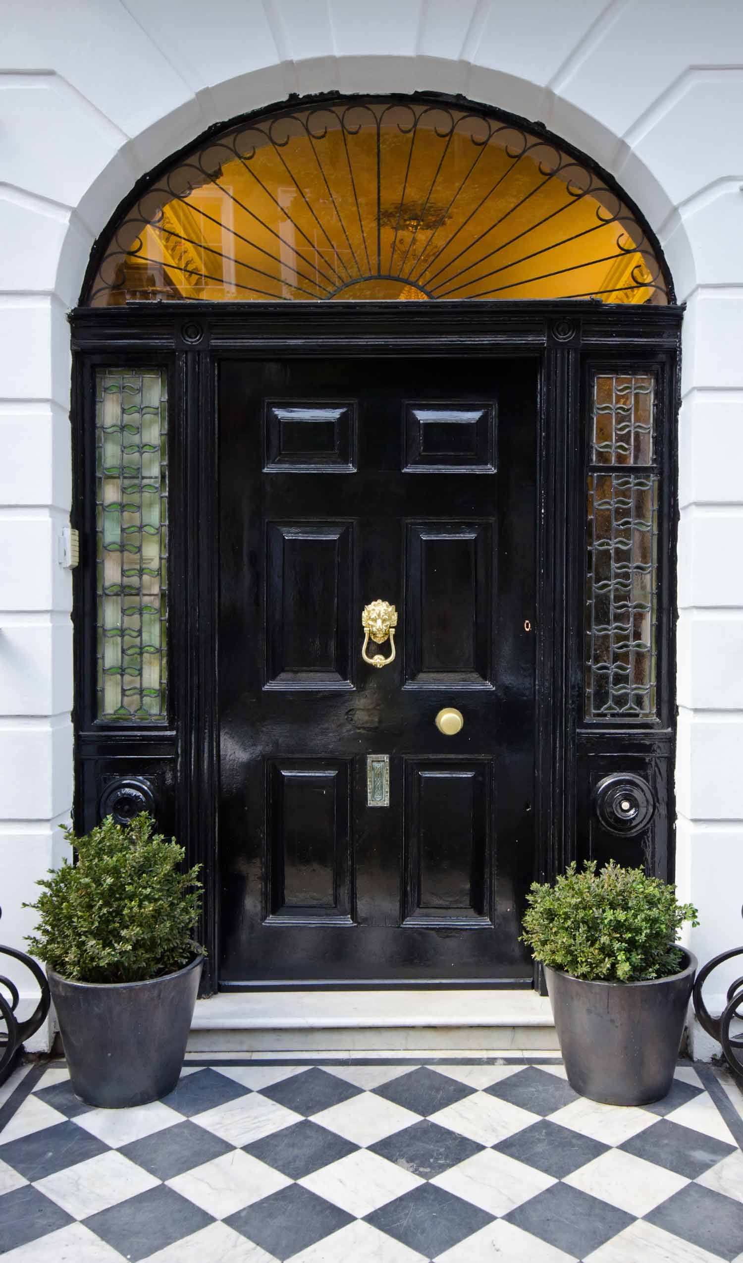2 French black door with gilding lion head knocker, two boxwoods and black and white chequered floor