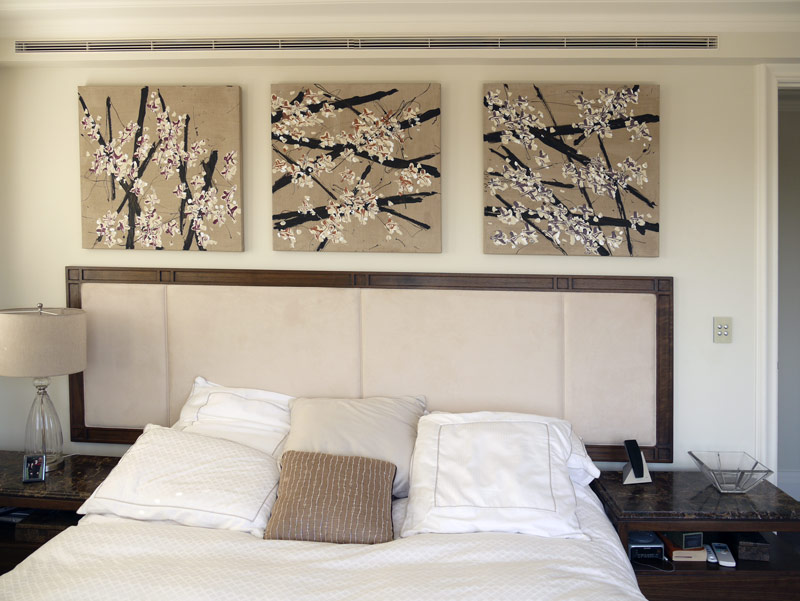 Three paintings above a bed